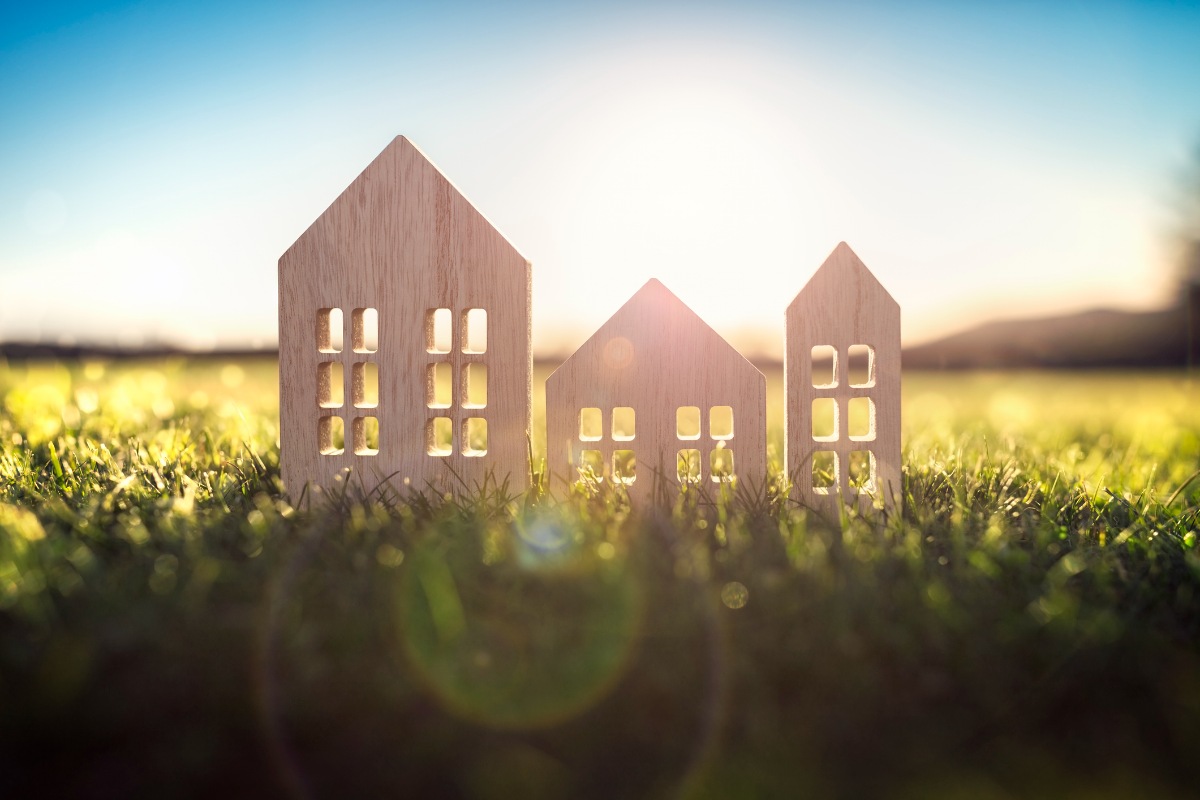 Ecological wood model house in empty field at sunset